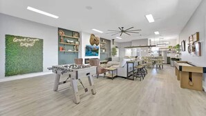 A spacious living area with a foosball table, a green wall with a 'Grand Canyon Outpost' sign, and a large window. - Hot Tub, Grill, Fire Pit / 25 mins to Grand Canyon (Grand Canyon Junction)