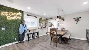 A modern kitchen with a neon sign, wooden furniture, and a green wall. - Hot Tub, Grill, Fire Pit / 25 mins to Grand Canyon (Grand Canyon Junction)