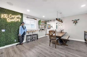 Una cocina moderna con un letrero de neón, muebles de madera y una pared verde.