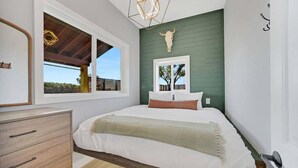 A bedroom with a bed, a dresser, a window with a view, and a wall-mounted bull skull decoration. - Hot Tub, Grill, Fire Pit / 25 mins to Grand Canyon (Grand Canyon Junction)
