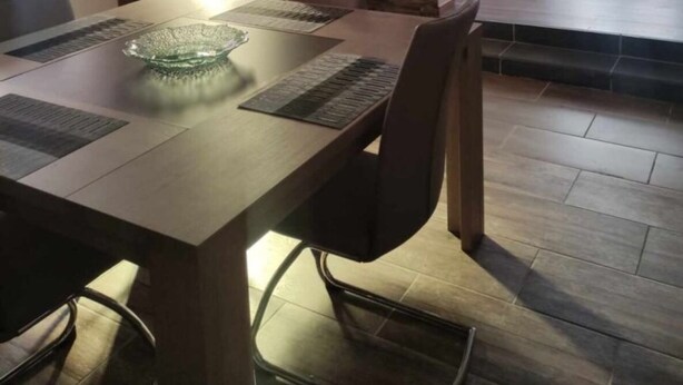 Ein moderner Essbereich mit einem Holztisch, Stühlen und einer Glasschale als Dekoration.