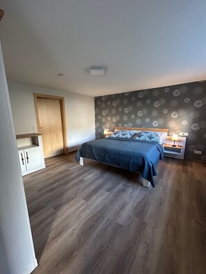 A bedroom with a bed, nightstands, a wardrobe, and a patterned wall.