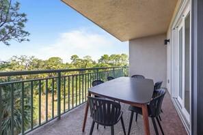 A balcony with a table and chairs, a green railing, and a view of trees. - Luxury Condo with Sanctuary Views Merritt Island (Merritt Island)