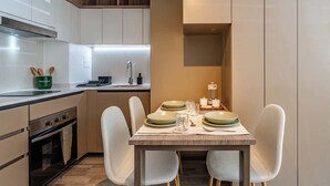 A modern kitchen with white cabinets, a dining table set with plates and glasses, and a built-in oven. - Charming 1BR in Santiago, WiFi & Equipped Kitchen (Unknown)