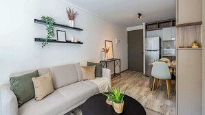 A modern living room with a sofa, coffee table, and a dining area with chairs and a table. - Charming 1BR in Santiago, WiFi & Equipped Kitchen (Unknown)