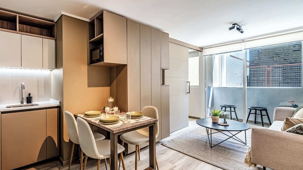 A modern kitchen with built-in appliances, a dining area with a table and chairs, and a seating area with a sofa and coffee table. - Charming 1BR in Santiago, WiFi & Equipped Kitchen (Unknown)