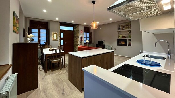 Cozinha moderna com ilha central, eletrodomésticos embutidos e uma grande janela.