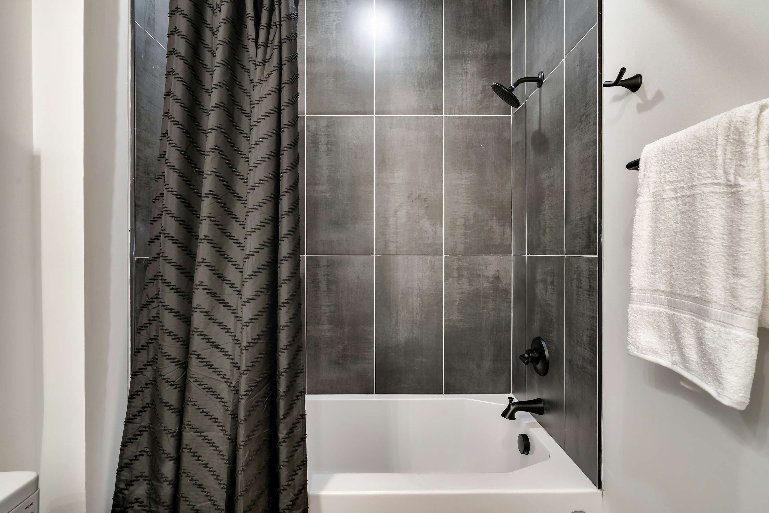 A modern bathroom with a bathtub, a shower, and a towel rack.