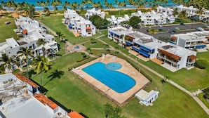 Un resort con una gran piscina, varias construcciones y vista al mar.
