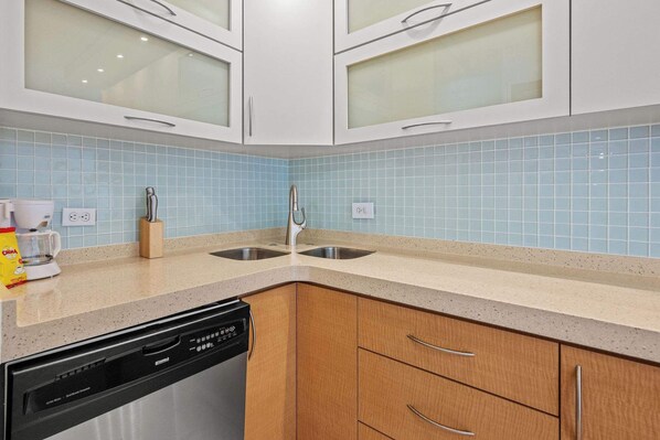 A kitchen with two sinks, a dishwasher, and a coffee maker.