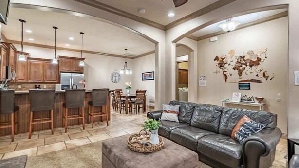 A modern kitchen with wooden cabinets, a dining area with a table and chairs, and a living room with a leather sofa and a coffee table. - Redterra - A Stunning Escape! (Hurricane)