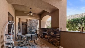An outdoor patio with a stone fireplace, a ceiling fan, and a dining table with chairs. - Redterra - A Stunning Escape! (Hurricane)
