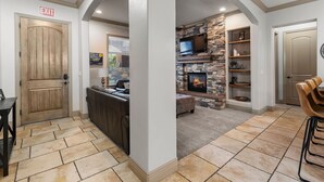 A spacious living area with a stone fireplace, a television mounted above it, and a cozy seating arrangement. - Redterra - A Stunning Escape! (Hurricane)