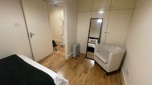 A bedroom with a bed, a chair, a wardrobe, and a mirror. - 2 Bed Apartment/ Tower Bridge / Big Ben /the Shard (London)