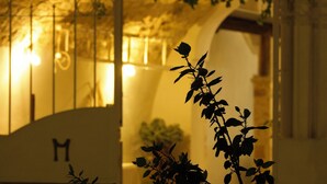 An arched doorway with a letter 'M' sign, surrounded by foliage. - masseria casamassima (Ostuni)