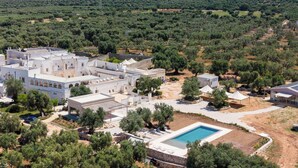 A coastal resort with white buildings, a swimming pool, and olive groves in the background. - masseria casamassima (Ostuni)