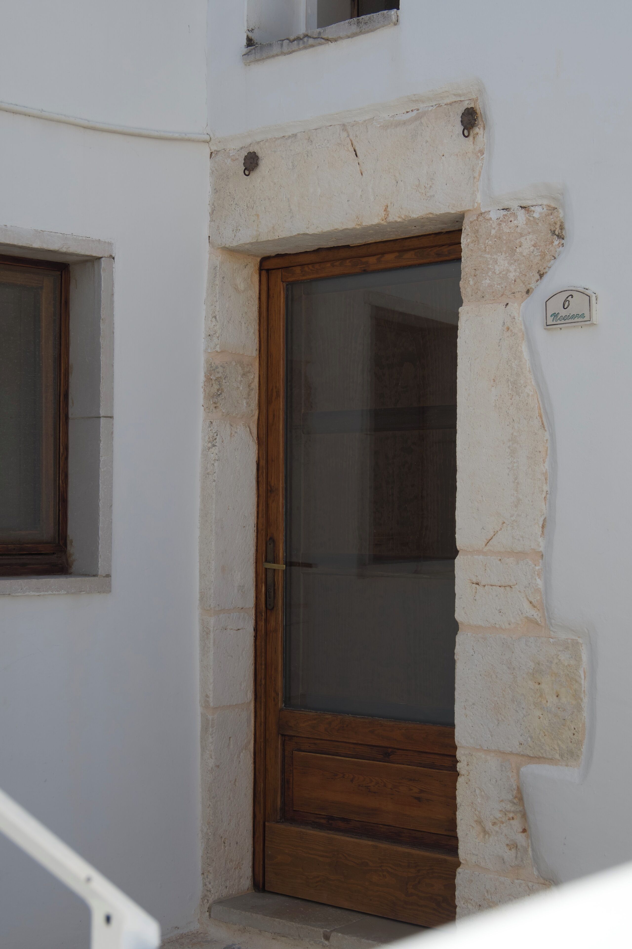 A white building with a wooden door and a small window.