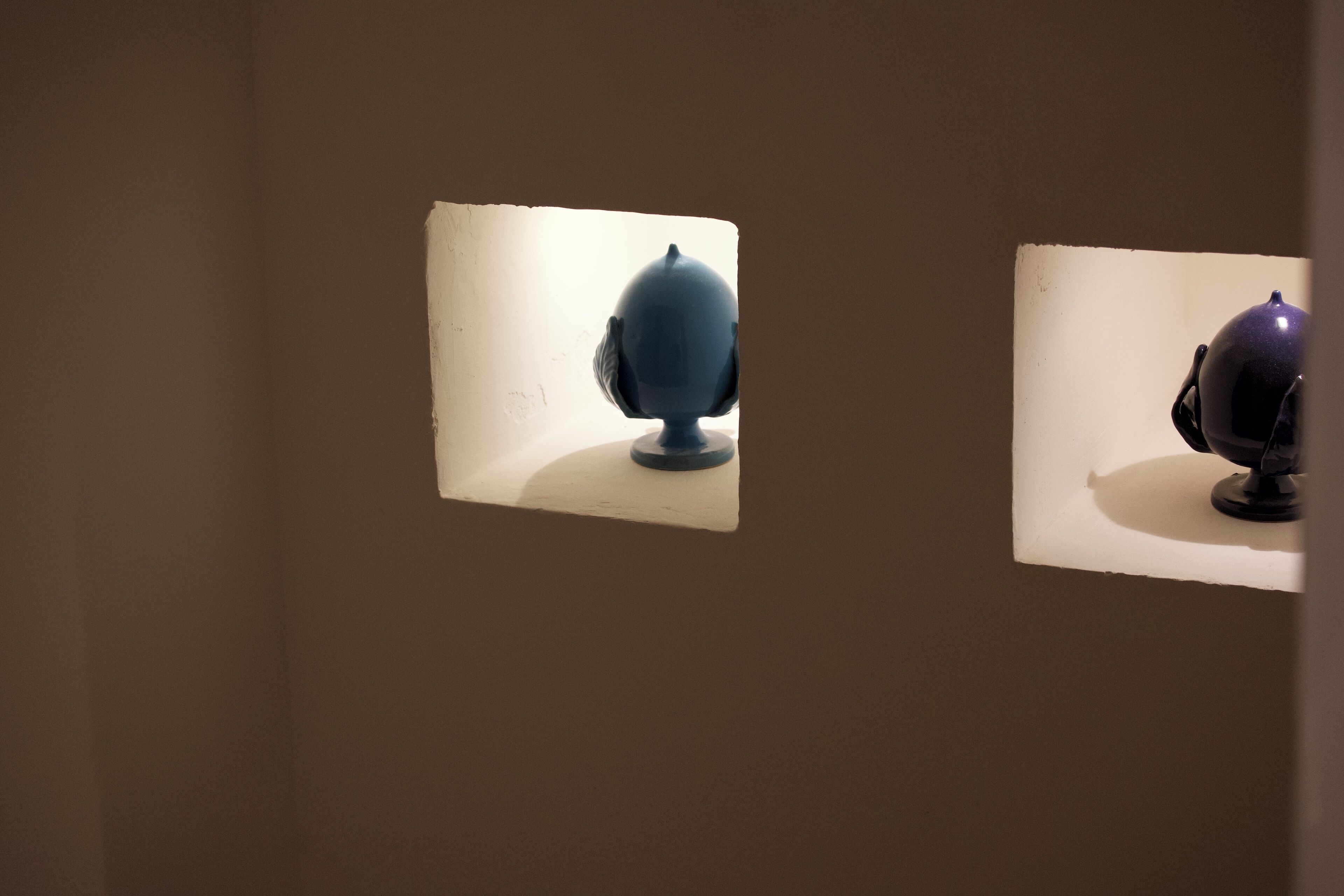 Two spherical objects on display against a plain wall.