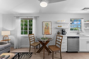 Una cocina moderna con armarios blancos, lavavajillas y ventana con vistas a zonas verdes.