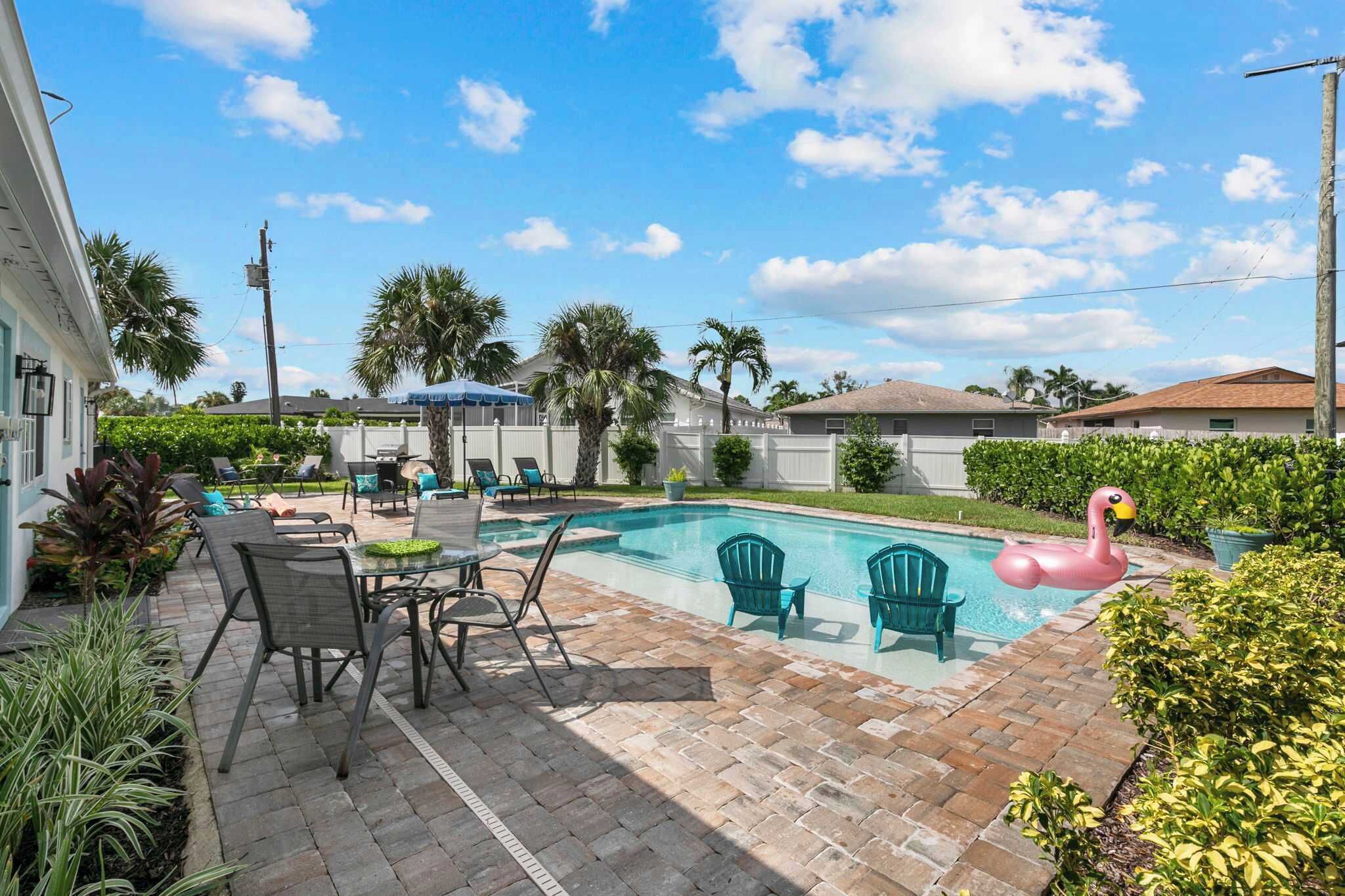 A backyard with a swimming pool, patio furniture, and a flamingo float.