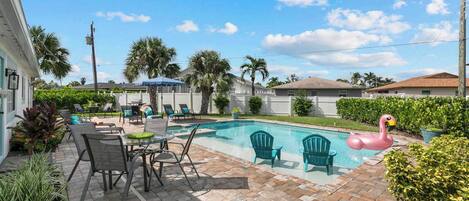 A backyard with a swimming pool, patio furniture, and a flamingo float.