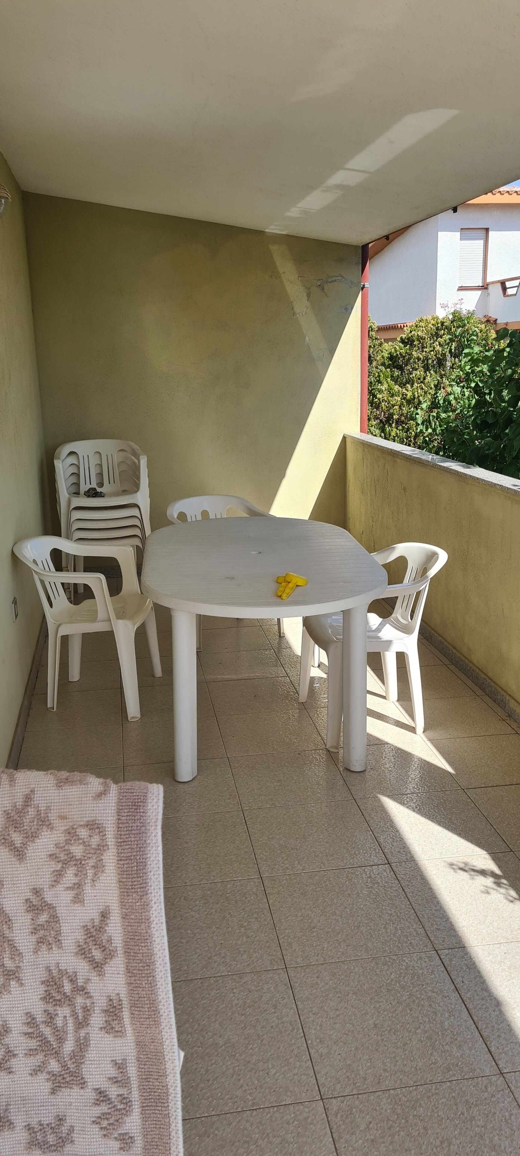 A small outdoor balcony with a round table and four white plastic chairs.