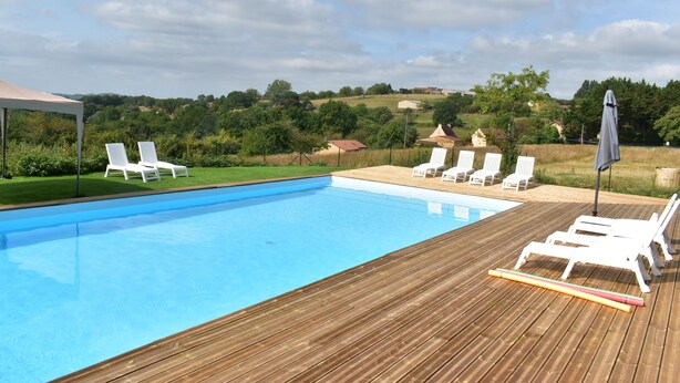 A swimming pool with white lounge chairs and a wooden deck.