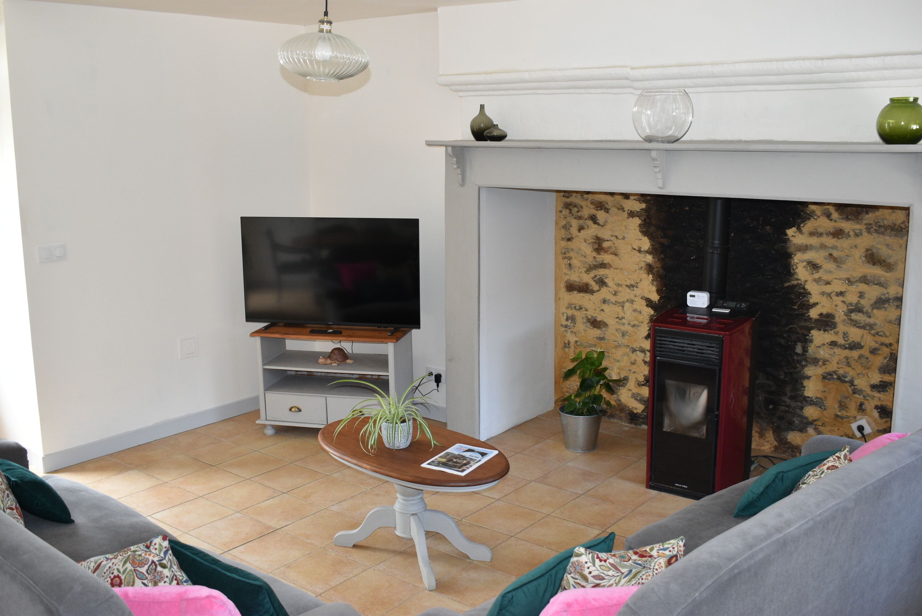 Una sala de estar con televisión, chimenea, sofá y una mesa con planta.