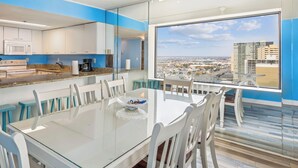 Een moderne keuken met een eethoek, grote ramen met uitzicht op de stad en een glazen tafel.