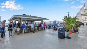 Een buitengedeeltelijk uitziende bar met een overdekt zitgedeelte en een podium voor optredens.