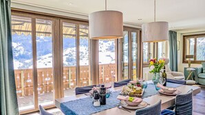 A dining area with a table set for four, large windows with a mountain view, and a balcony with a wooden railing. - Nice apartment for 4 guests with WIFI, TV and balcony (Unter Eiger)