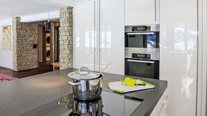 A modern kitchen with a stone accent wall, built-in appliances, and a central island. - Nice apartment for 4 guests with WIFI, TV and balcony (Unter Eiger)