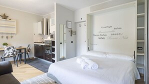 Ein modernes Hotelzimmer mit Bett, Schreibtisch und einer Küchenzeile.
