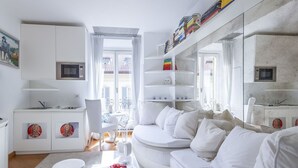 Ein modernes, helles Wohnzimmer mit einem weißen Sofa, einem Essbereich und einer Küche.