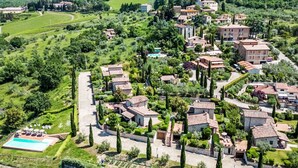 An aerial view of a residential area with houses, a swimming pool, and a castle in the background. - Beautiful apartment in villa for 2 guests with WIFI, A/C, pool, TV and pets allowed (Gaiole In Chianti)