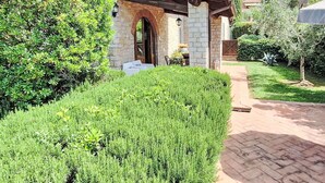 A stone house with a tiled roof, a covered patio, and a well-maintained garden. - Beautiful apartment in villa for 2 guests with WIFI, A/C, pool, TV and pets allowed (Gaiole In Chianti)