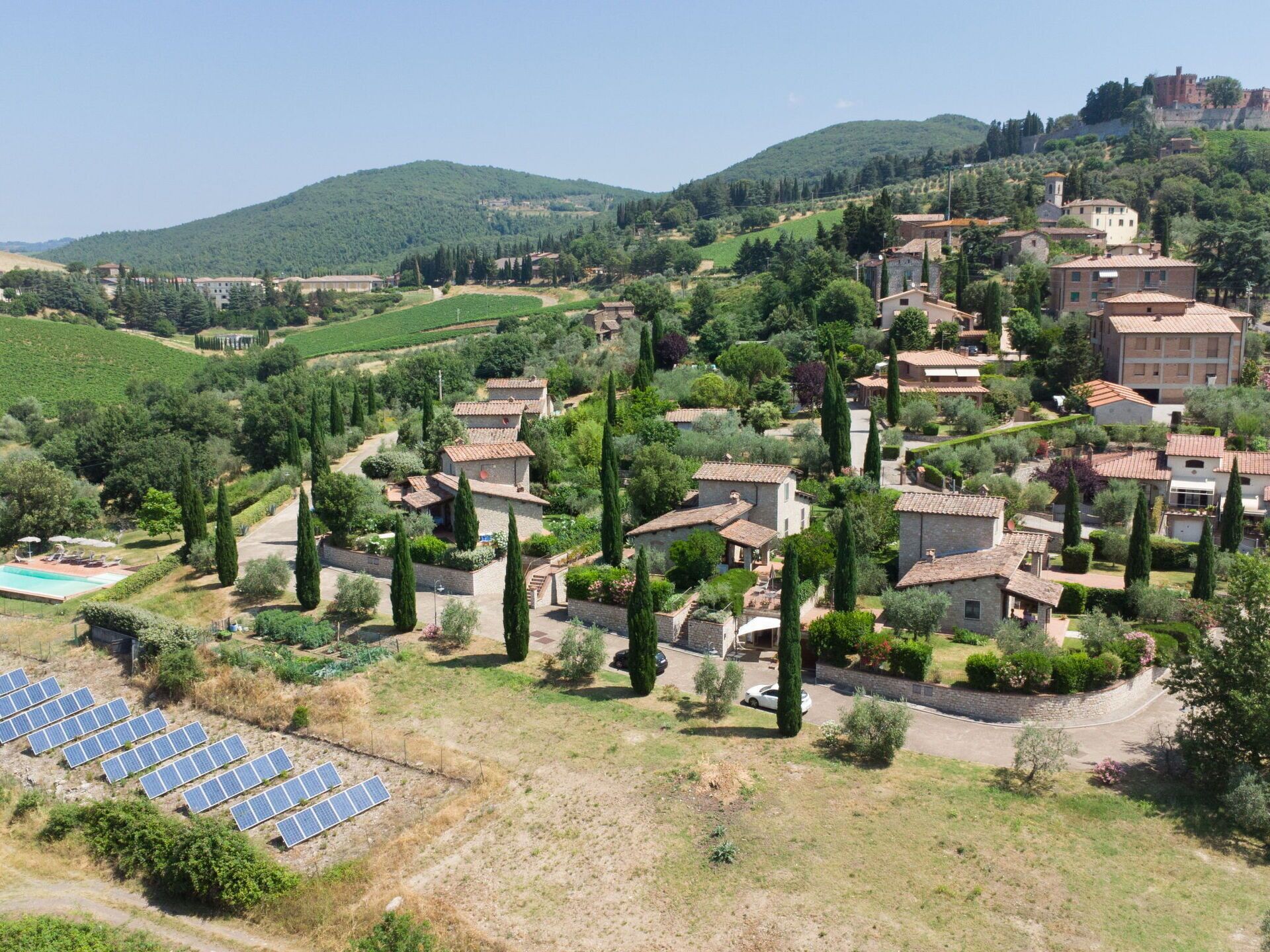 A rural village with traditional stone houses, a vineyard, and solar panels.