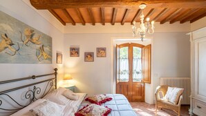 A bedroom with a bed, a chair, a door, and a painting on the wall. - Beautiful apartment in villa for 4 people with pool, A/C, WIFI, TV and pets allowed (Gaiole In Chianti)