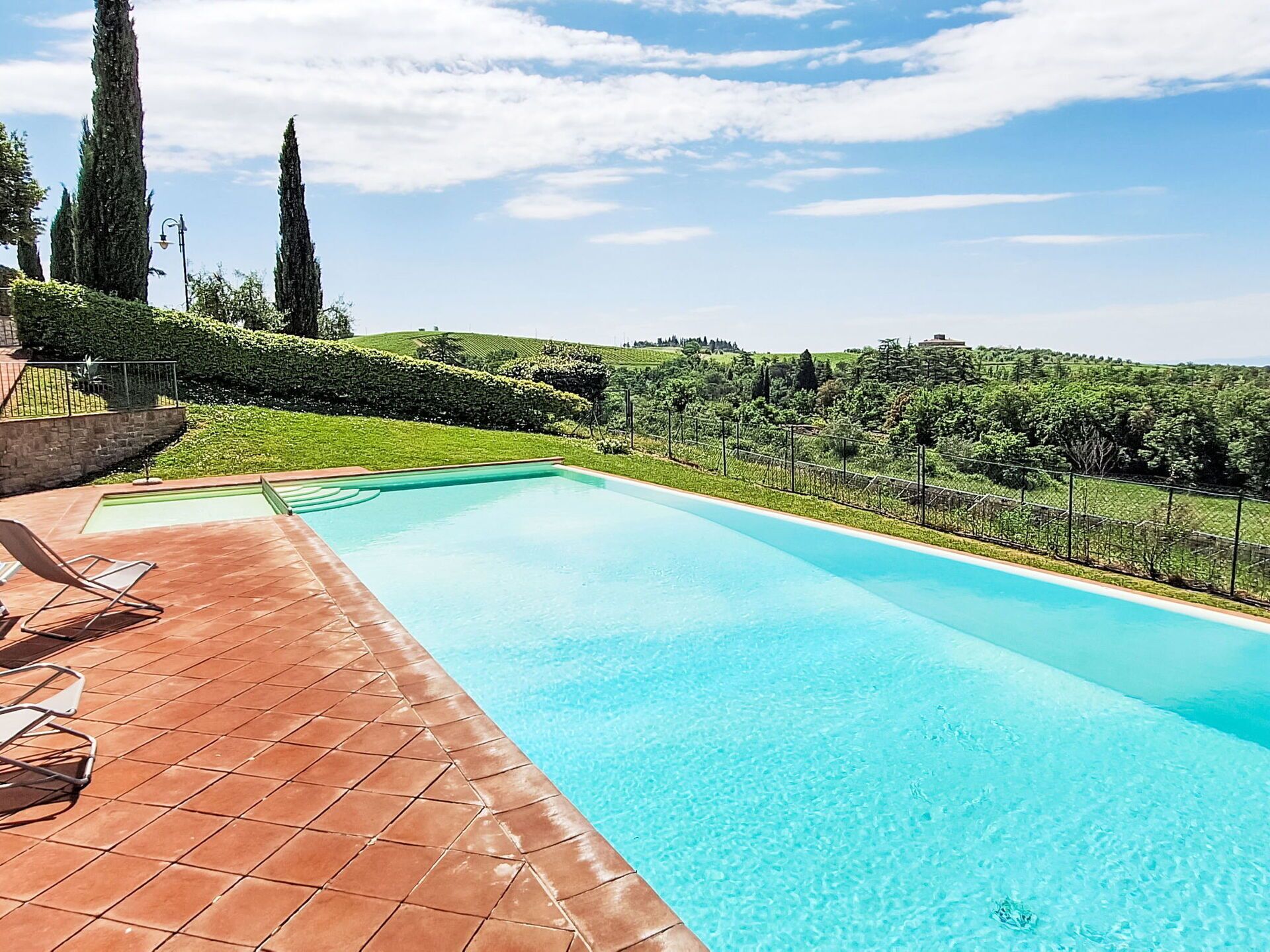 Una piscina rectangular amb una terrassa enrajolada i gandules.