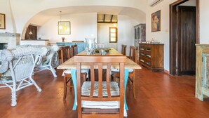 Un comedor con mesa y sillas de madera, un sofá de mimbre y una chimenea.