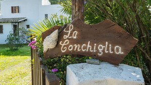 Un letrero de madera rústico con la inscripción "La Conchiglia" en un jardín.