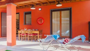 An outdoor patio with a wooden ceiling, a dining table with chairs, and two sun loungers. - Nice apartment for 6 people with A/C, WIFI, TV and patio (Viareggio)