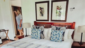 A hotel room with a large bed, two wall-mounted picture frames, a wooden headboard, and a tiled floor. - Kruger Island Resort (White River)