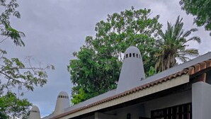 A building with a flat roof, multiple windows, and a covered outdoor seating area with chairs. - Kruger Island Resort (White River)