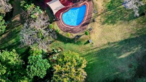 An aerial view of a residential property with a swimming pool, a fenced yard, and a house with a sloped roof. - Kruger Island Resort (White River)