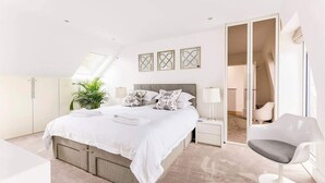 A modern bedroom with a large bed, a desk, a chair, and a wardrobe.