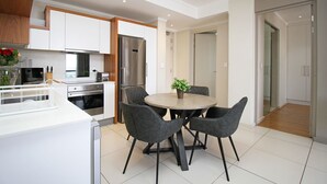 Una cocina moderna con armarios blancos, un refrigerador de acero inoxidable y un comedor con una mesa redonda y cuatro sillas.