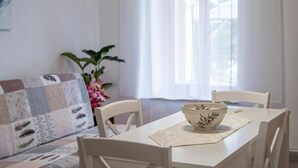 A dining area with a table, chairs, a bowl, and a window with curtains. - Comfortable Apartment in Umag With Parking Space (Umag)