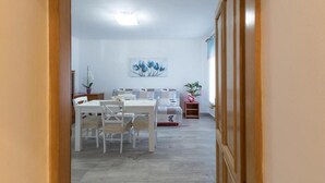 A dining area with a table and chairs, a sofa, and a painting on the wall. - Comfortable Apartment in Umag With Parking Space (Umag)