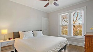 Ein Schlafzimmer mit Bett, Nachttisch, Lampe und Deckenventilator.